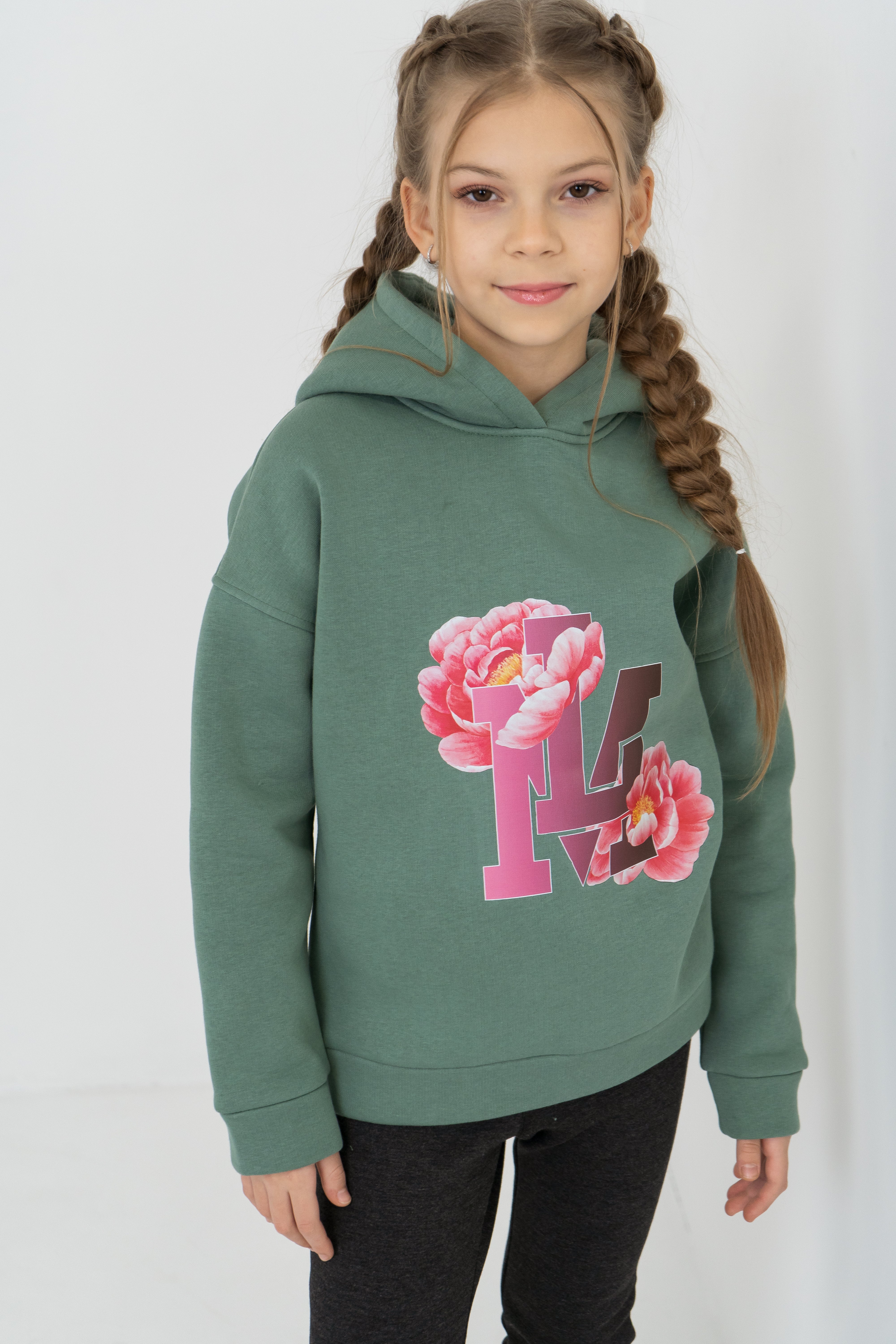 Mädchen im olivgrünen warmen Kapuzenpullover mit Blumen-Print ist bereit in die Schule zu gehen.