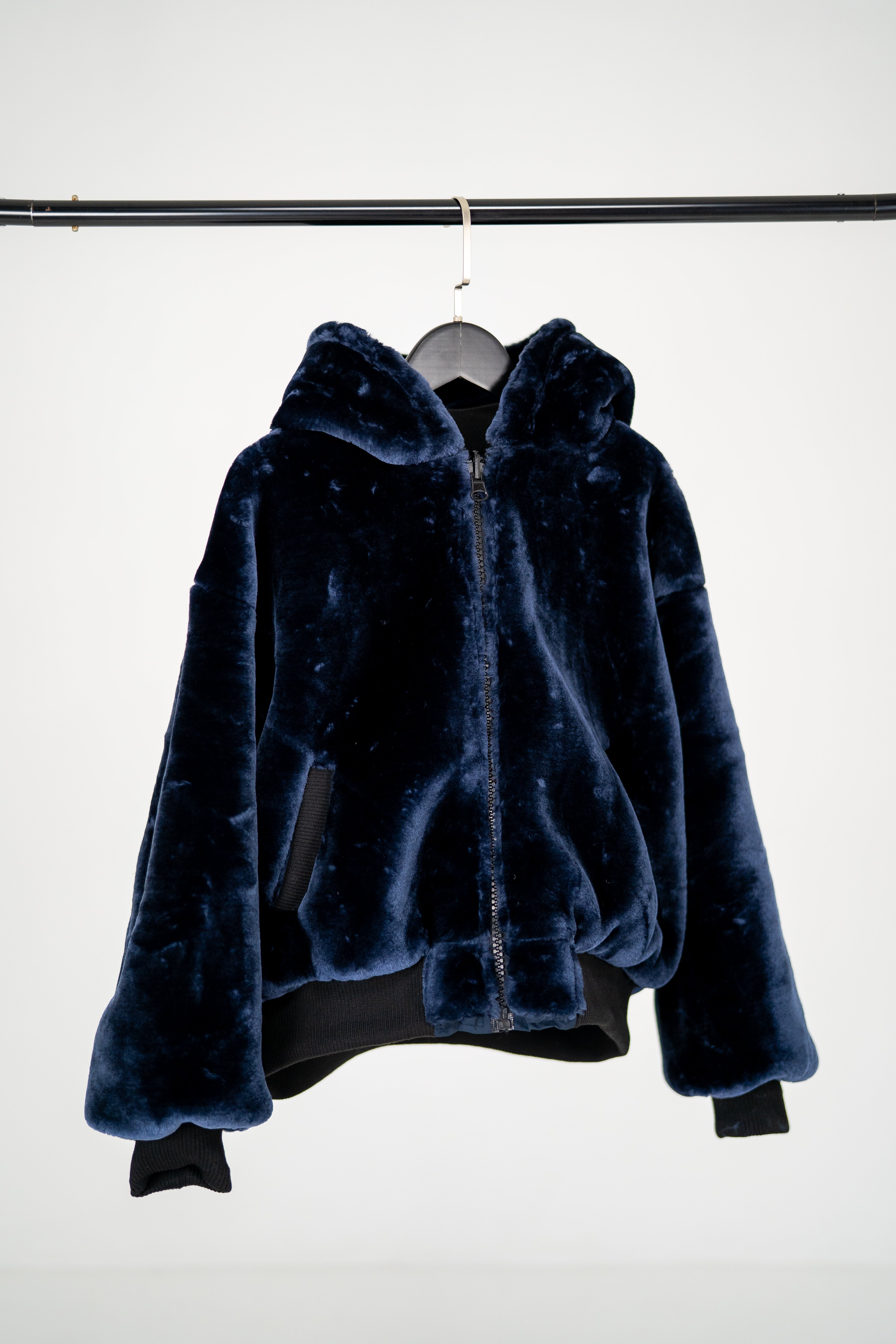 Dunkelblaue Winterjacke 2in1 mit Kapuze aus Kunstfell für Mädchen ist mit Fell nach außen gewendet und geschlossen.