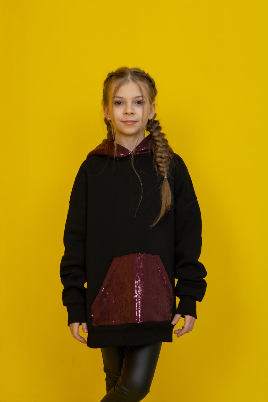black hoodie with a red sequin panel against a yellow background